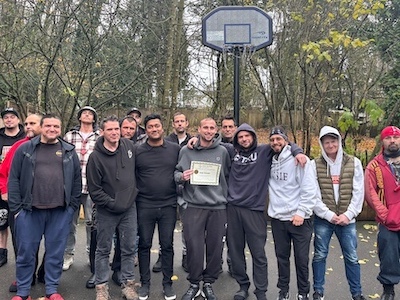 Inpatient Treatment 9 Men outside standing below basketball hoop posing for a picture